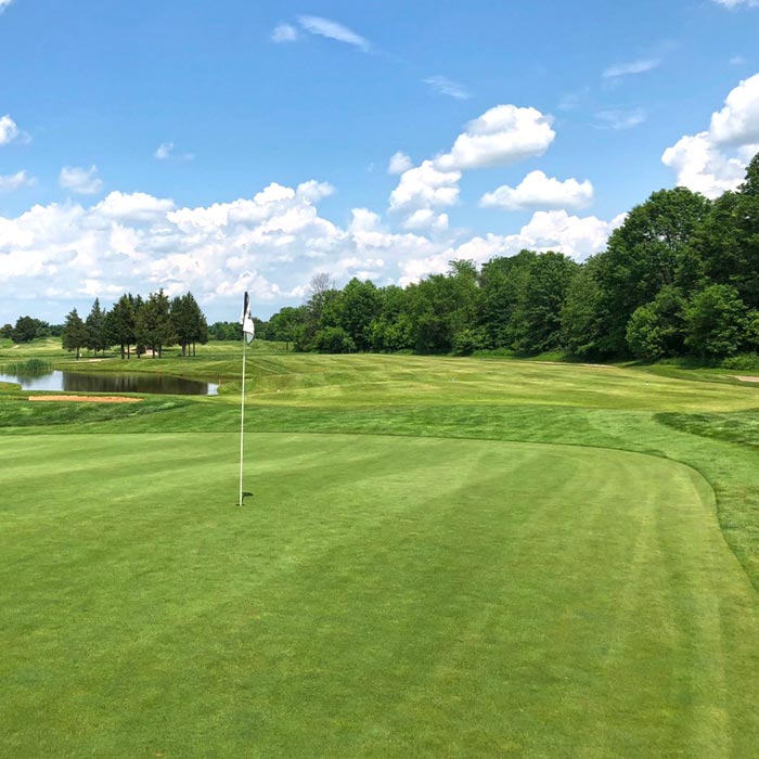 Golf course fairway with flag on hole near pond
